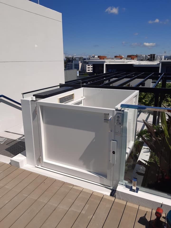 A White Box Is Sitting on Top of A Wooden Deck Next to A Building — Master Lifts Cairns in Cairns, QLD
