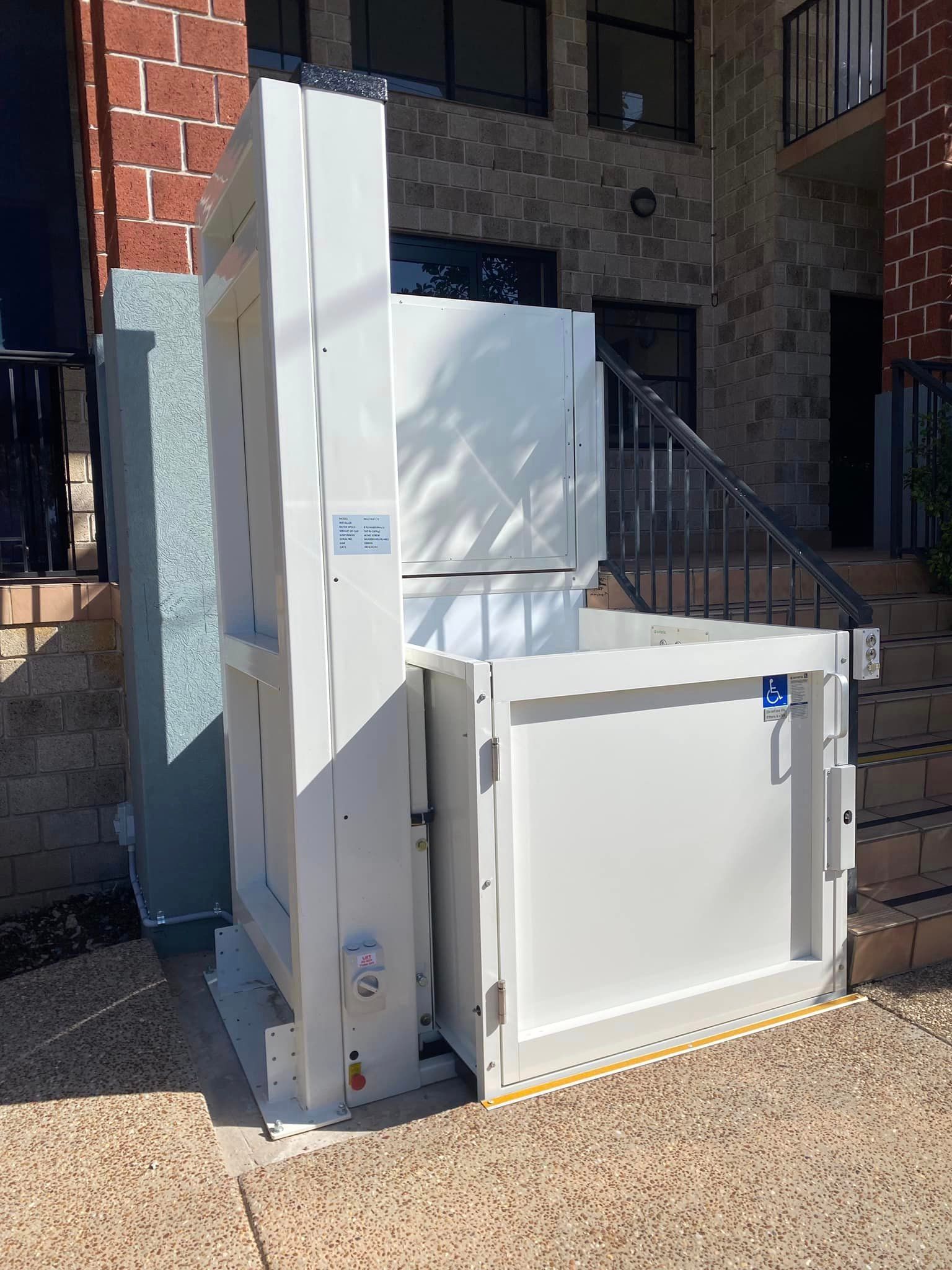A White Stair Lift Is Sitting in Front of A Building — Master Lifts Cairns in Cairns, QLD