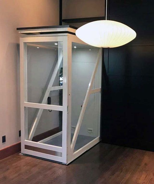 A White Elevator Is Sitting in A Room Next to A Lamp — Master Lifts Cairns in Cairns, QLD