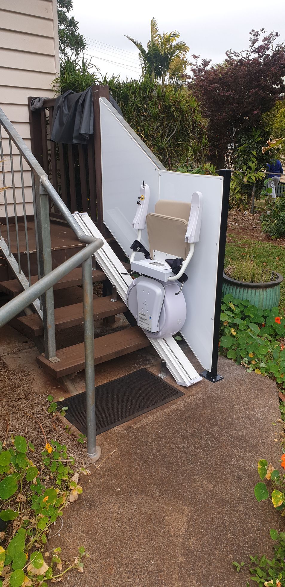 A stair lift is attached to the side of a house.