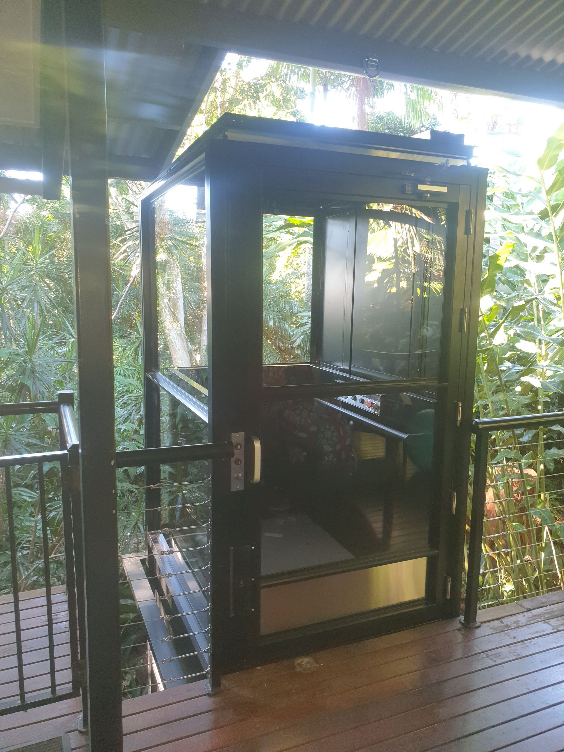 A Black Elevator Is Sitting on A Wooden Deck Surrounded by Trees — Master Lifts Cairns in Cairns, QLD