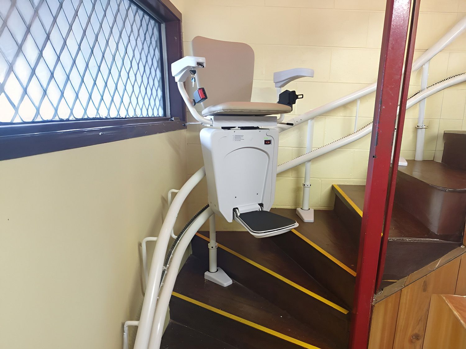 Stair Lift On Curved Wooden Staircase With Yellow Markings