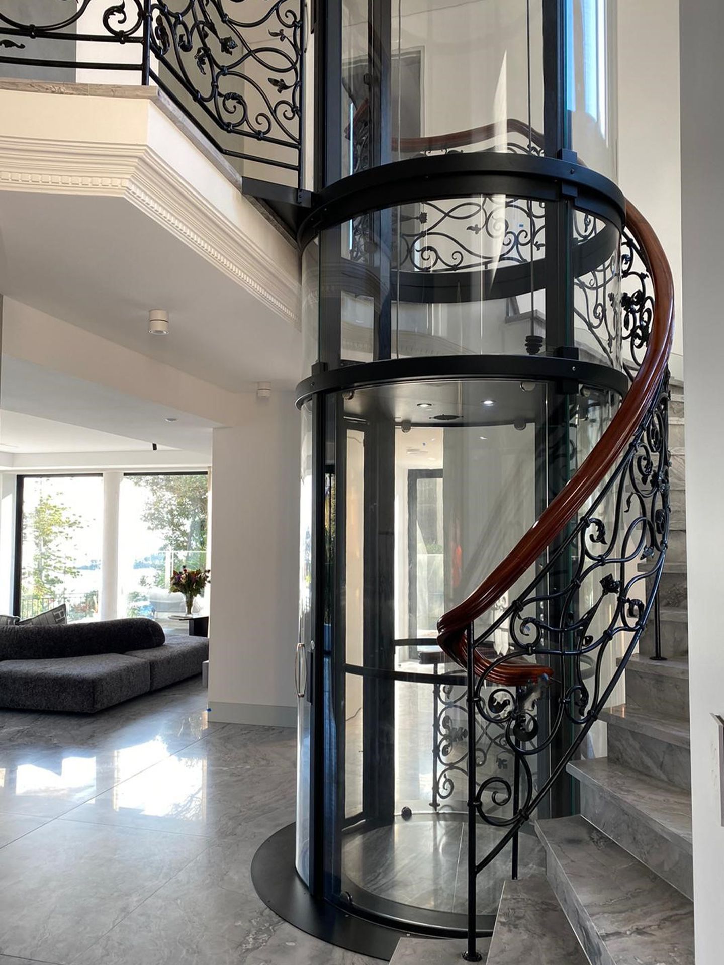 A Glass Elevator with A Spiral Staircase in A House — Master Lifts Cairns in Cairns, QLD