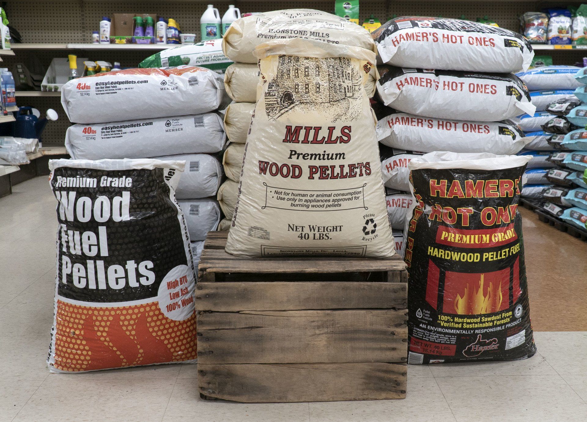 Wood pellet bags stacked in a store: Mills, Slammer, and others, on a wooden pallet.