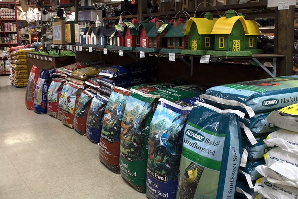 Bags of birdseed displayed in a store, with birdhouses above.
