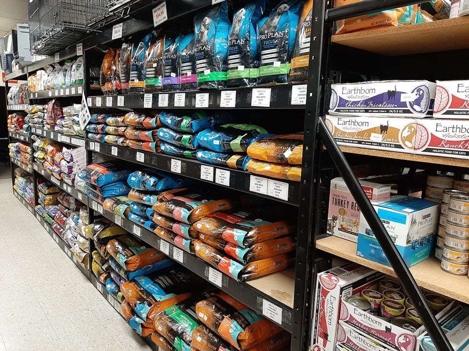 Shelves stocked with various pet food bags in a store; several brands and colors visible.