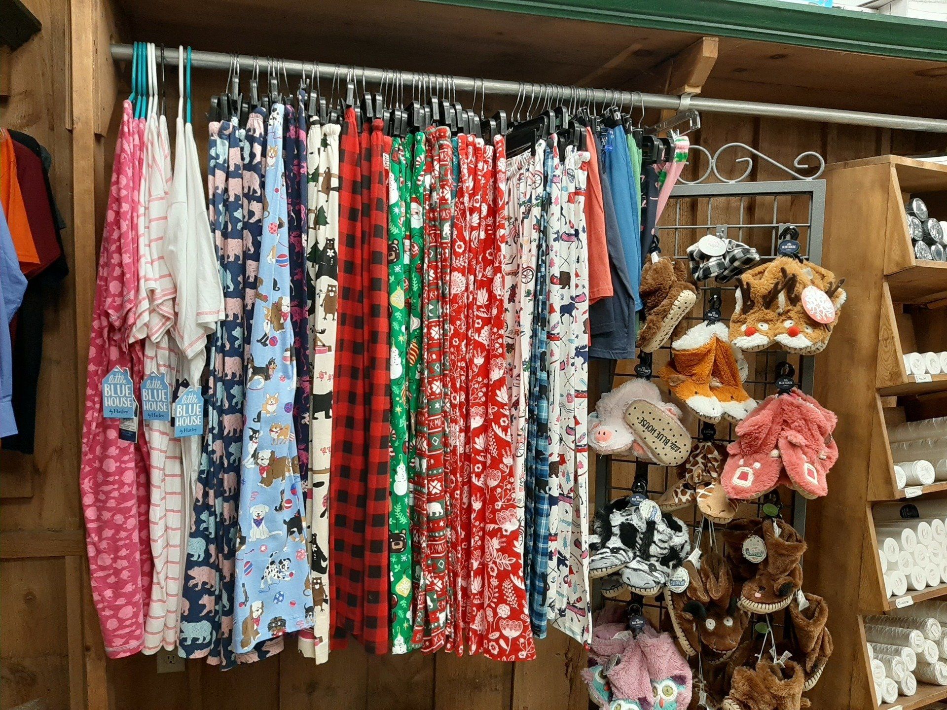 Clothes rack with patterned pants and stuffed animal slippers in a shop.