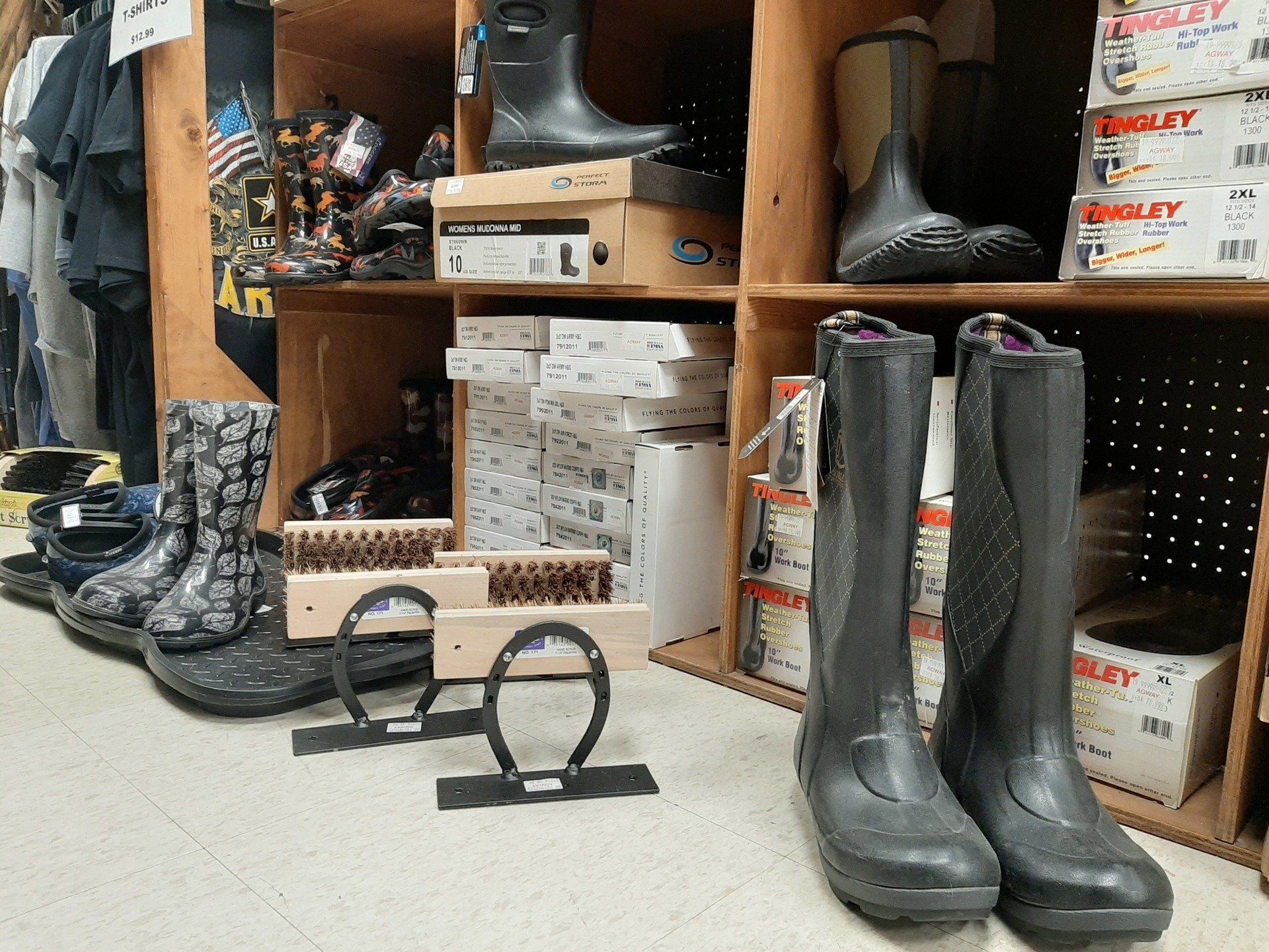 Boots on shelves in a store. Gray and black boots are on display, with boot racks in front.