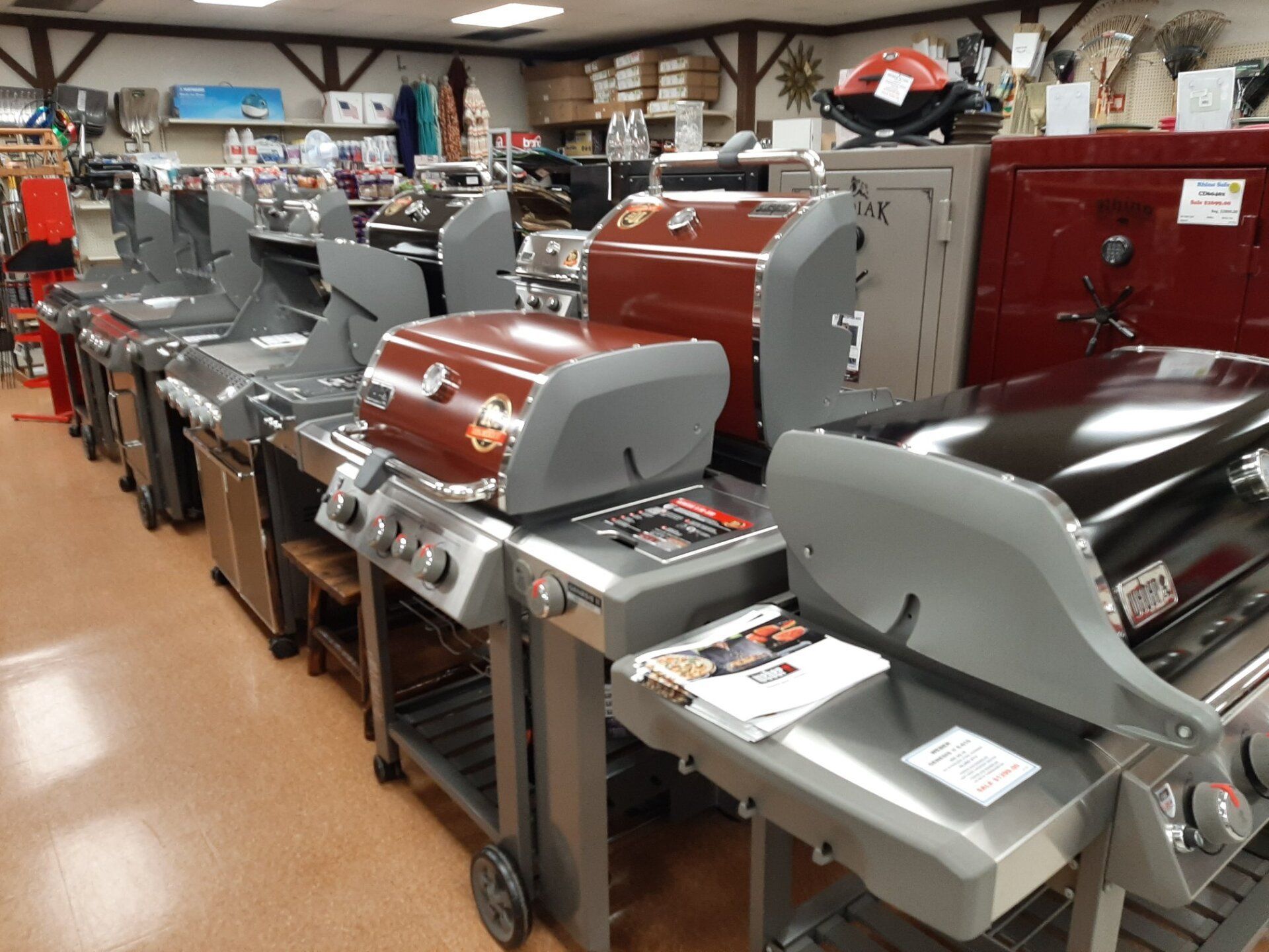 Row of grills on display inside a store with red and silver exteriors.