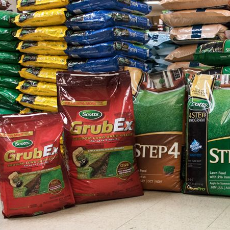 Bags of Scotts lawn products: GrubEx, Step 4, various colors stacked in a store.