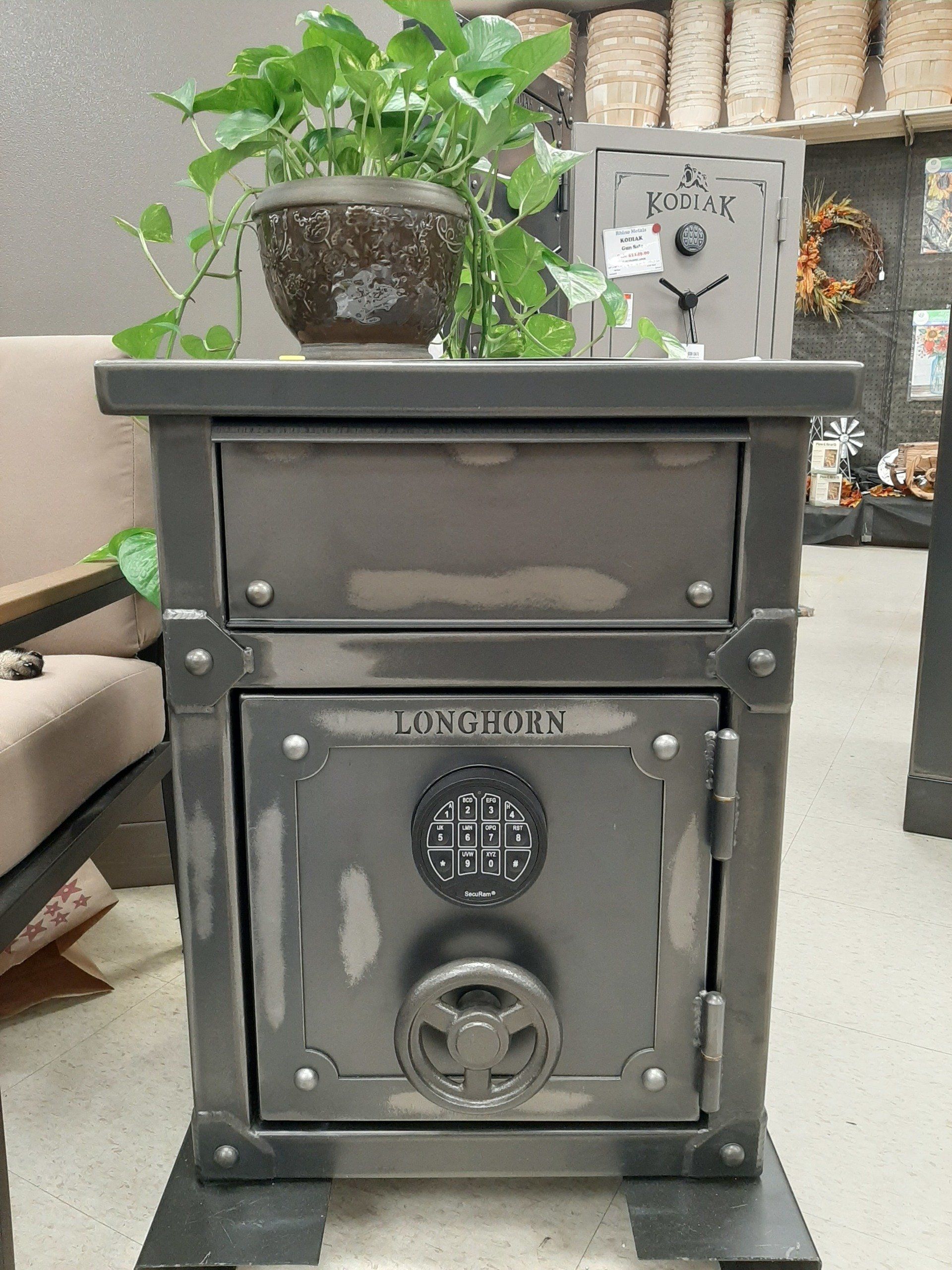Gray safe with a combination dial, drawer, and plant on top.