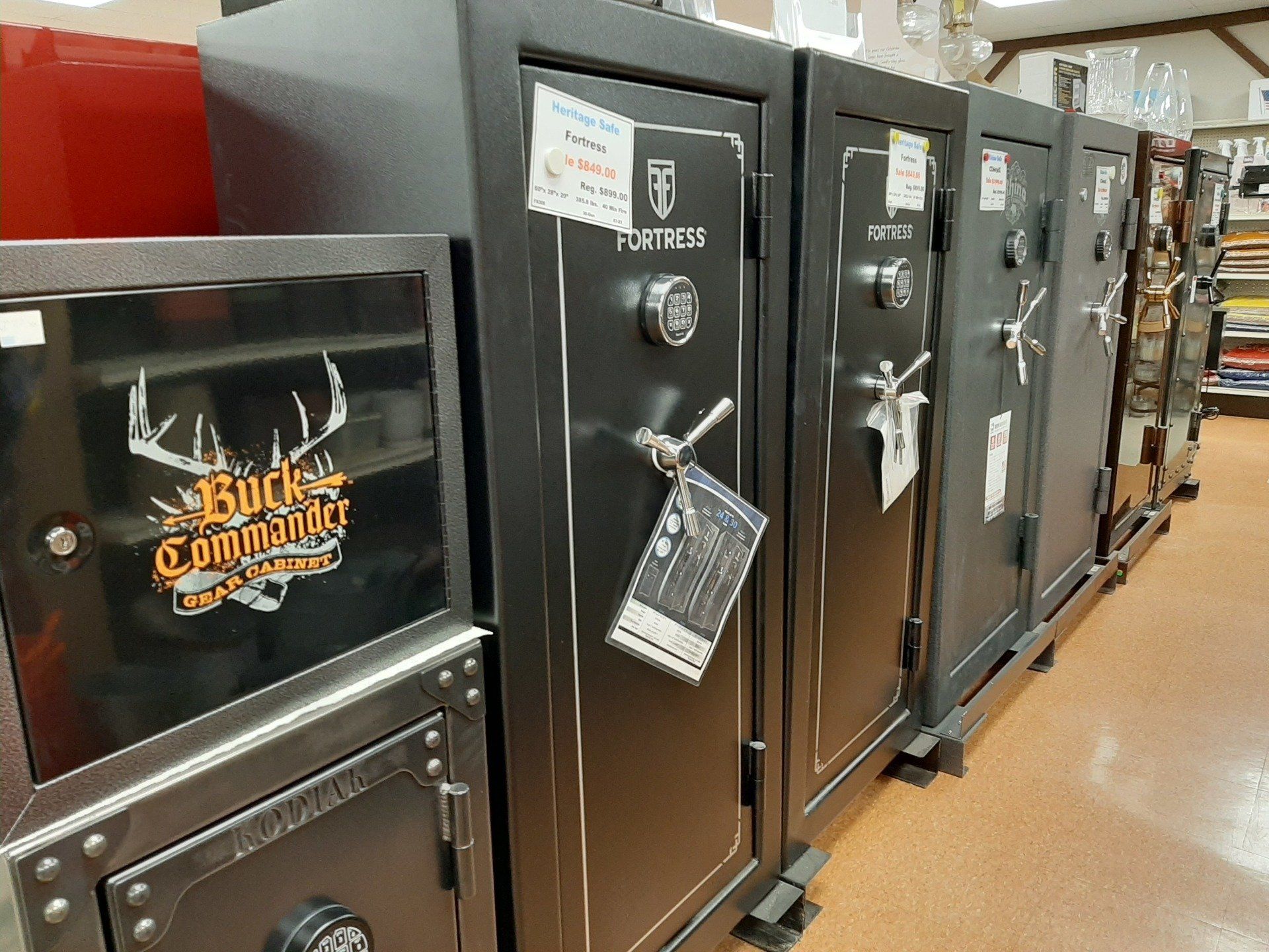 A row of dark safes in a store, including ones labeled 