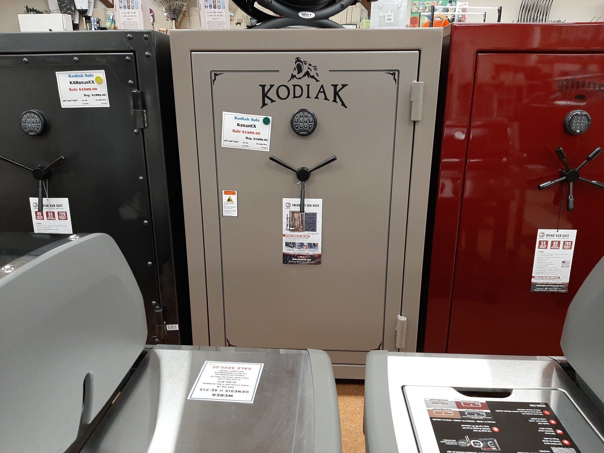 A tan Kodiak safe displayed between a black and red safe in a store setting.