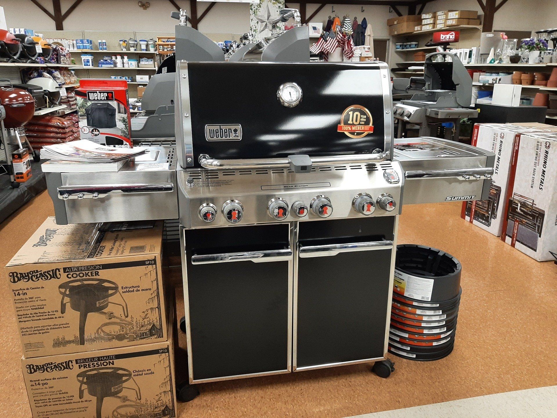Black gas grill with stainless steel surfaces, indoors.