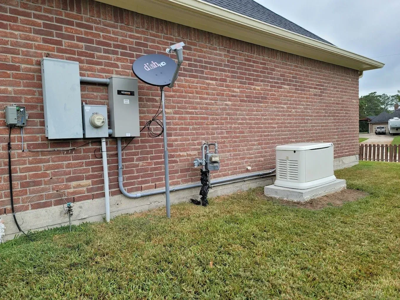 A brick house with a generator and satellite dish on the side of it.