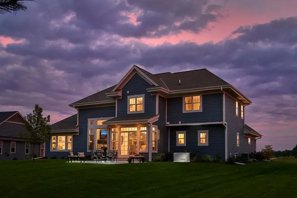 A large blue house with a lot of windows is lit up at night.