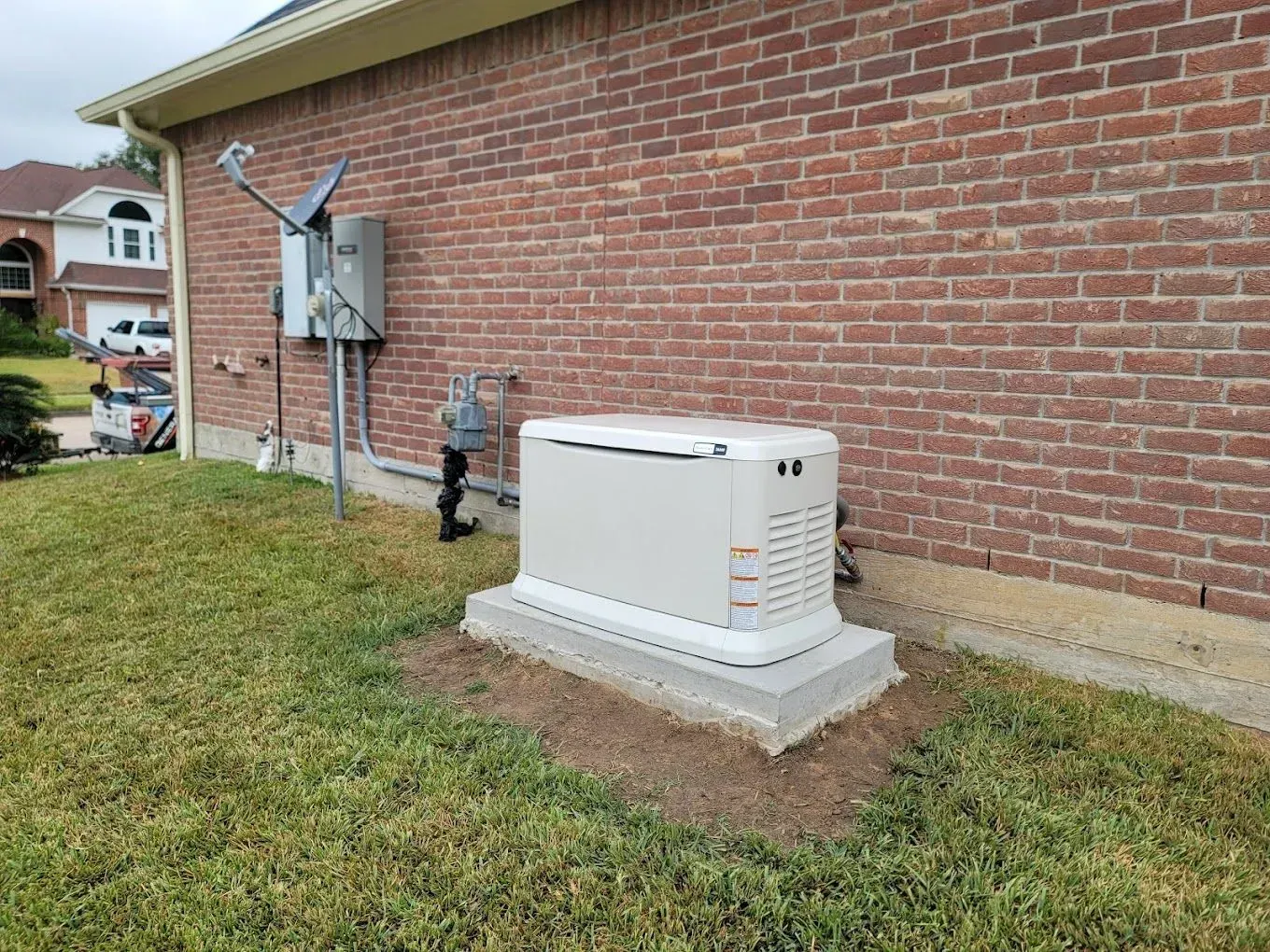 A generator is sitting on the side of a brick house.
