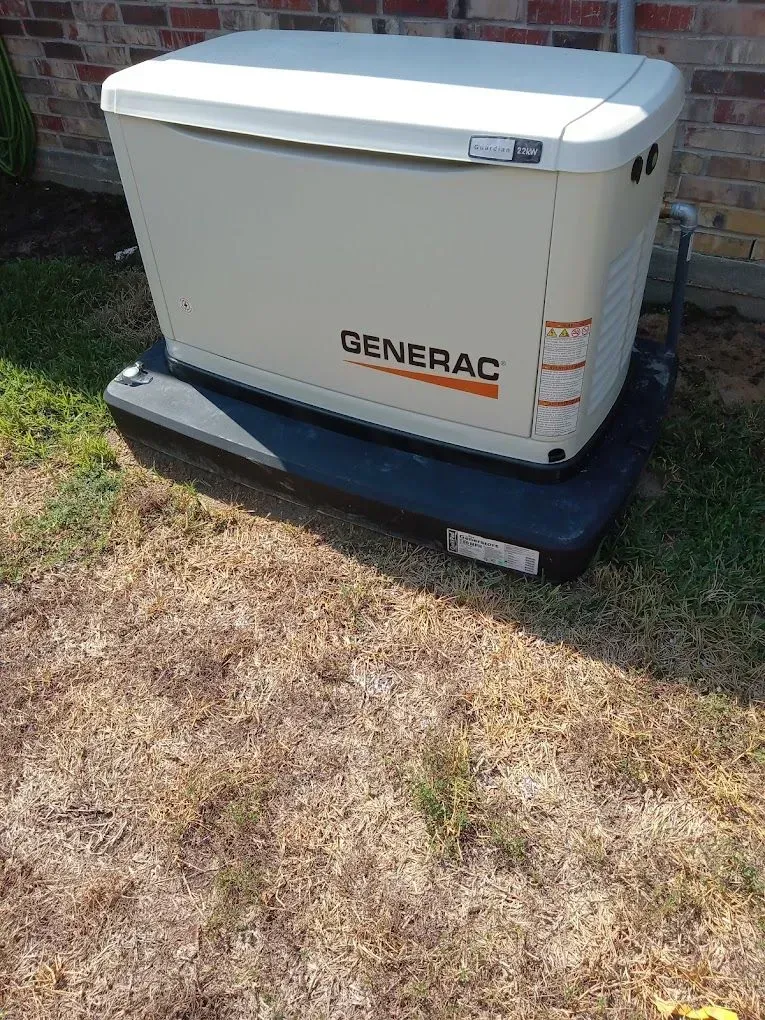 A generator is sitting in the grass next to a brick building.