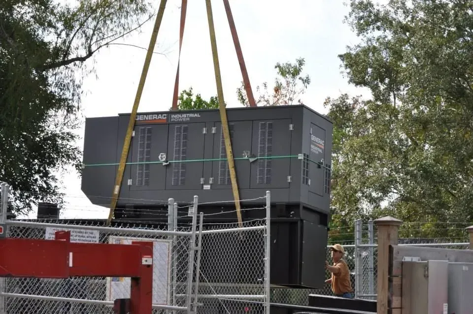 A large generator is being lifted by a crane.