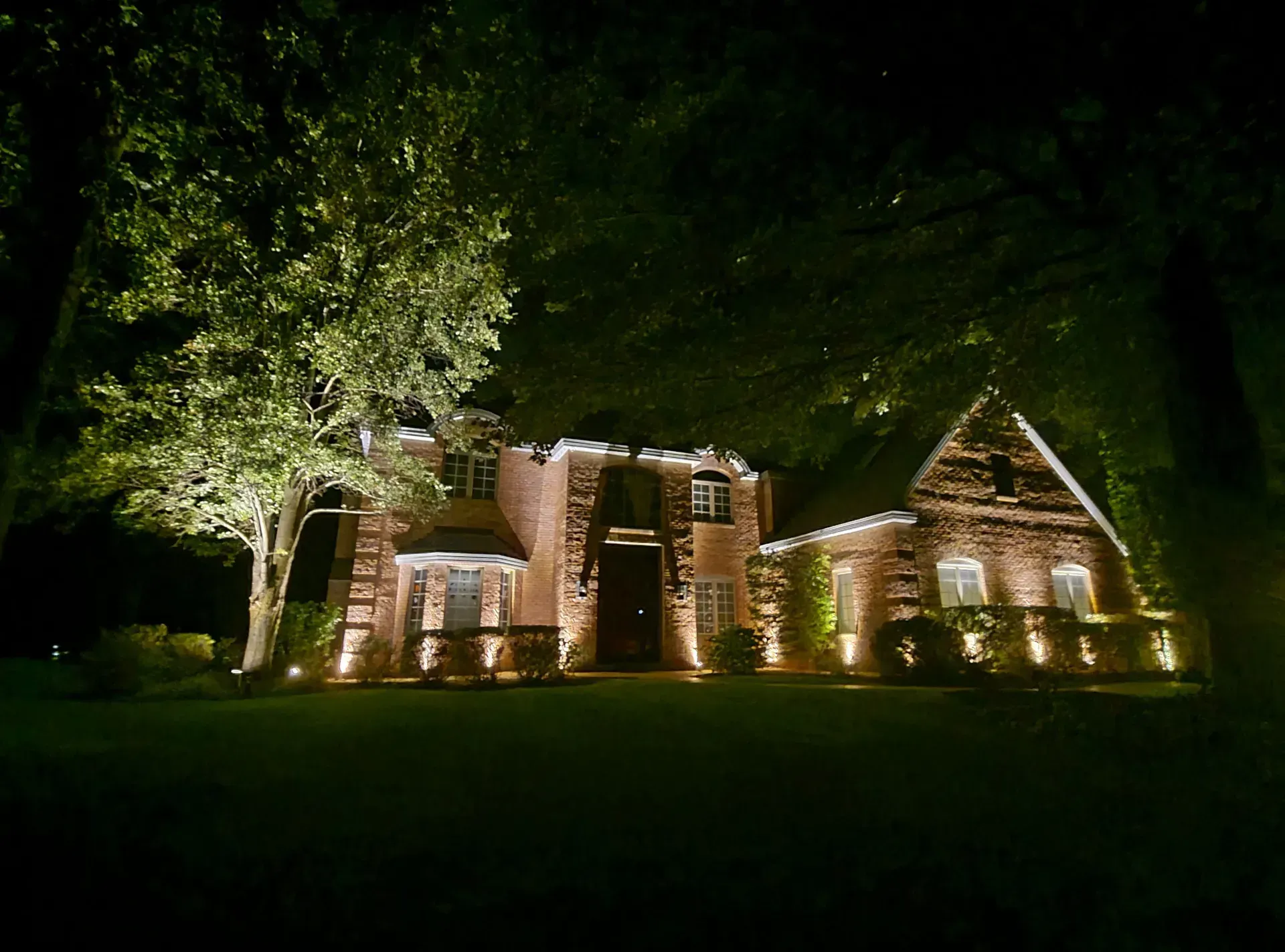 A large brick house is lit up at night.