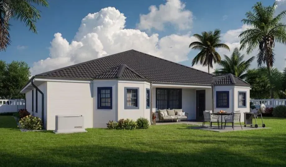 A white house with a black roof is sitting on top of a lush green lawn.