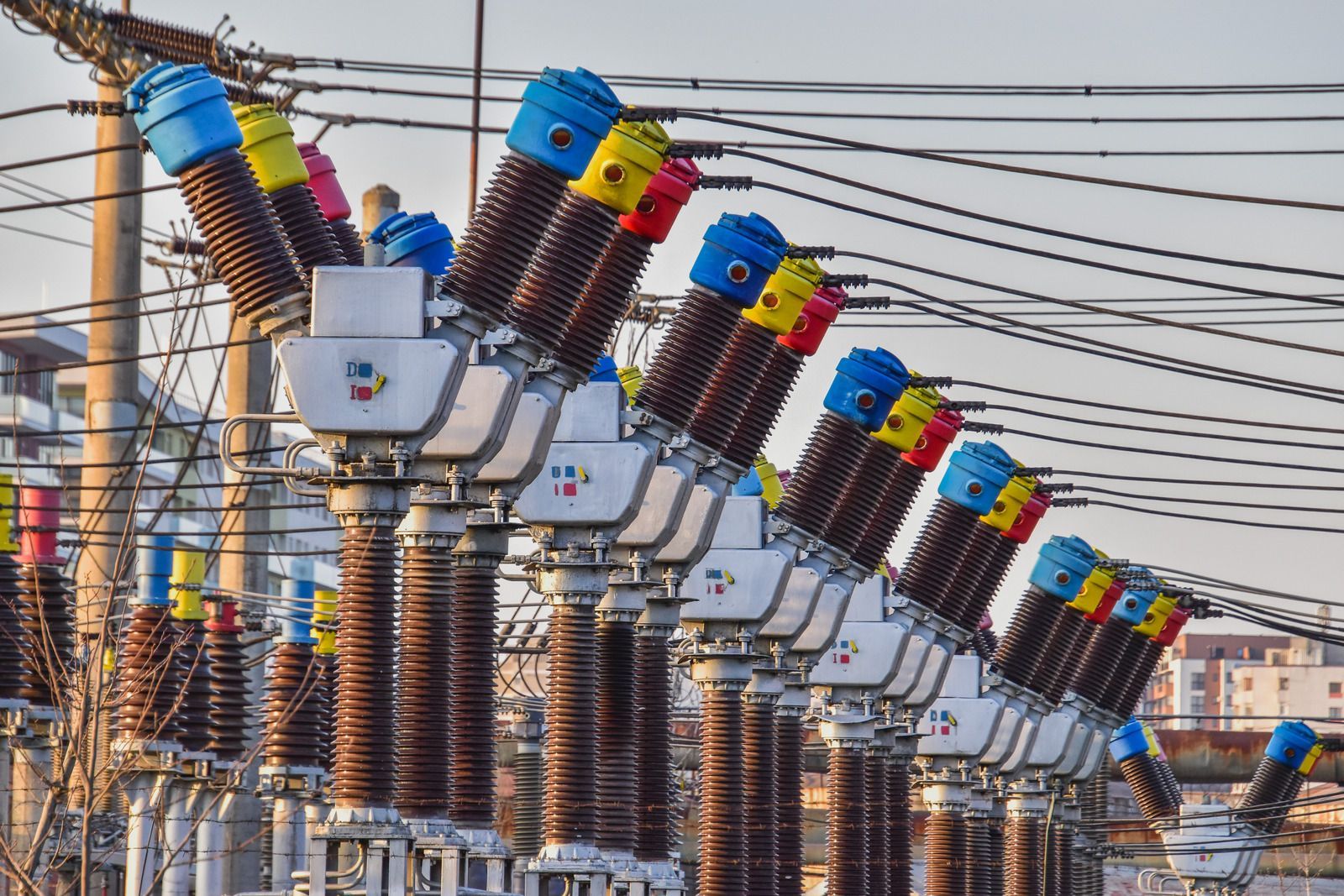 A bunch of electrical transformers are lined up next to each other.