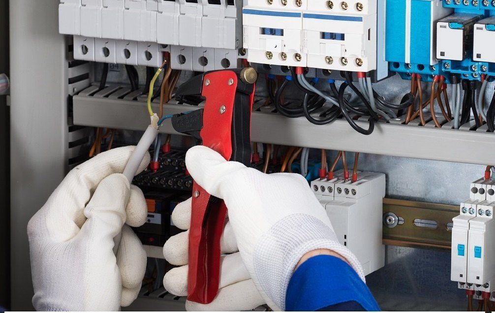 A person wearing white gloves is working on an electrical box