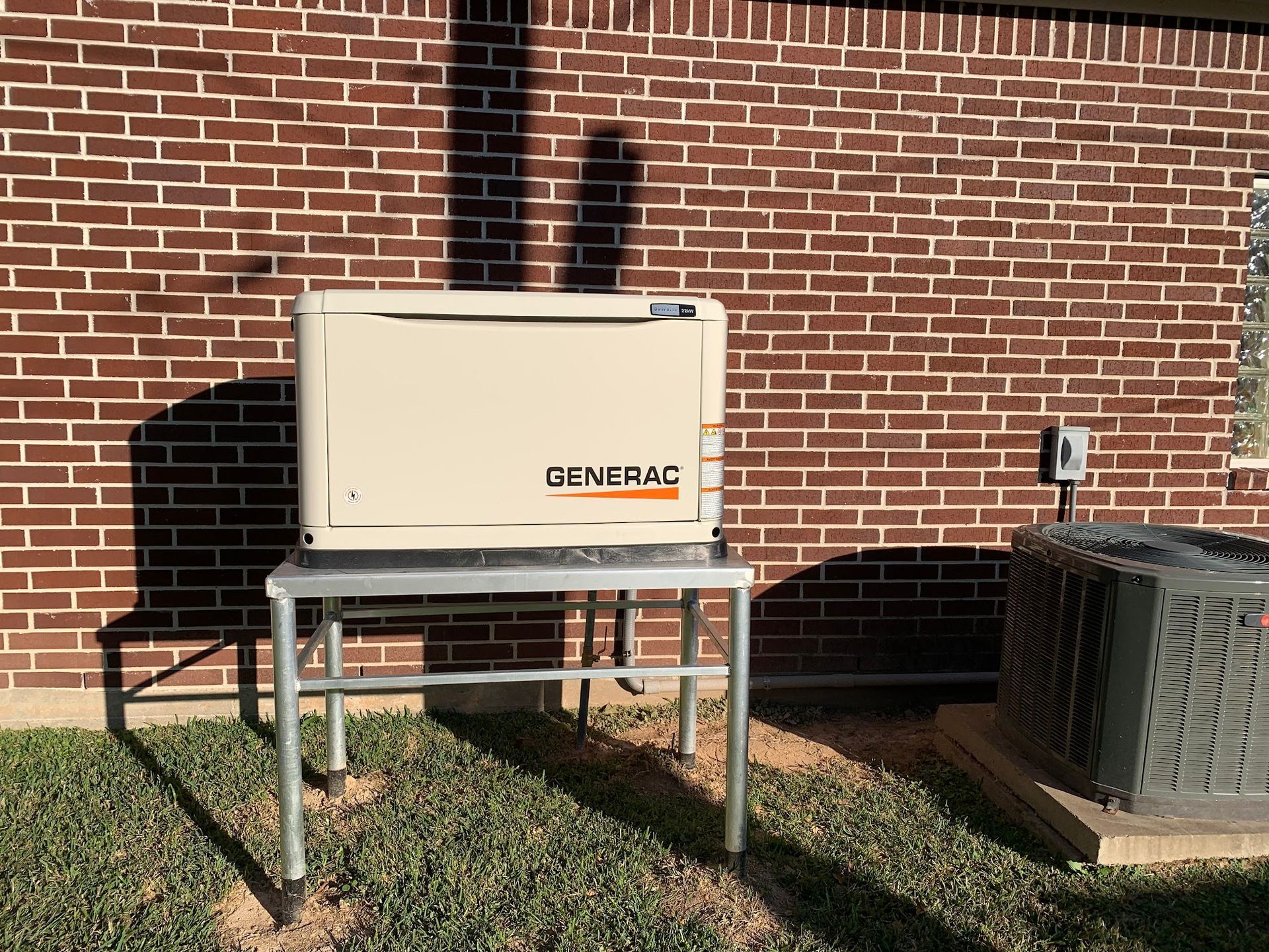 A generator is sitting on top of a metal table in front of a brick building.