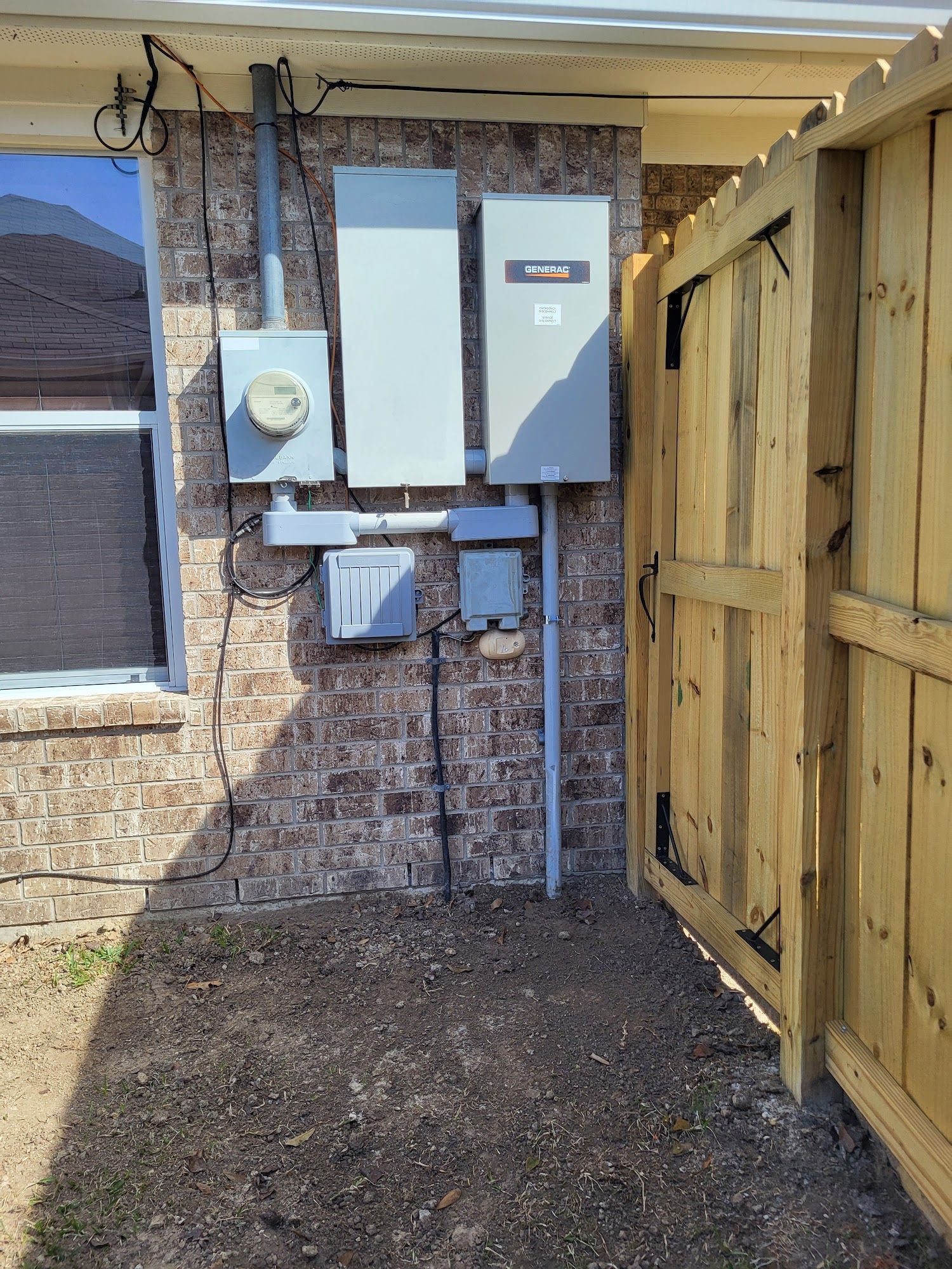 A brick building with a wooden fence and electrical panels on it.