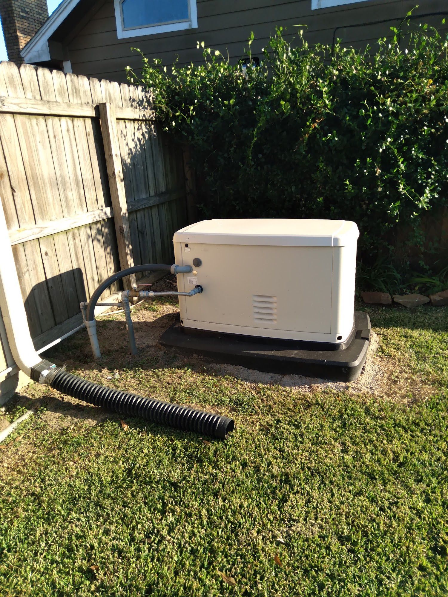 A white box is sitting in the grass next to a fence.