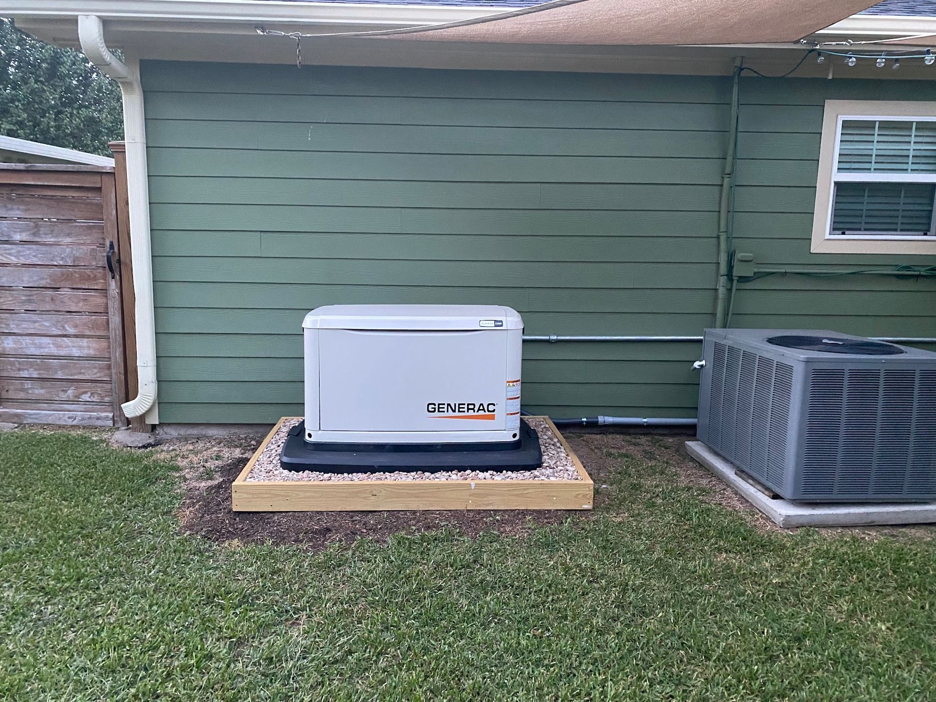 A generator is sitting on the side of a house next to an air conditioner.