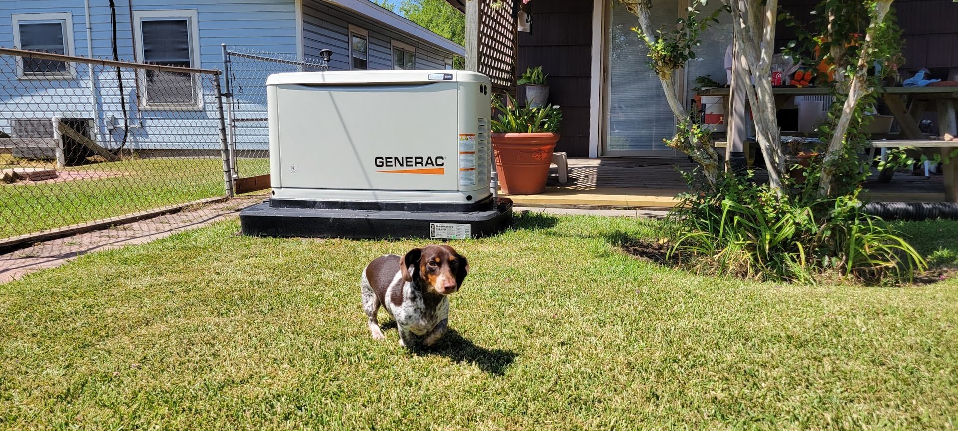 A dog is running in the grass in front of a generator.