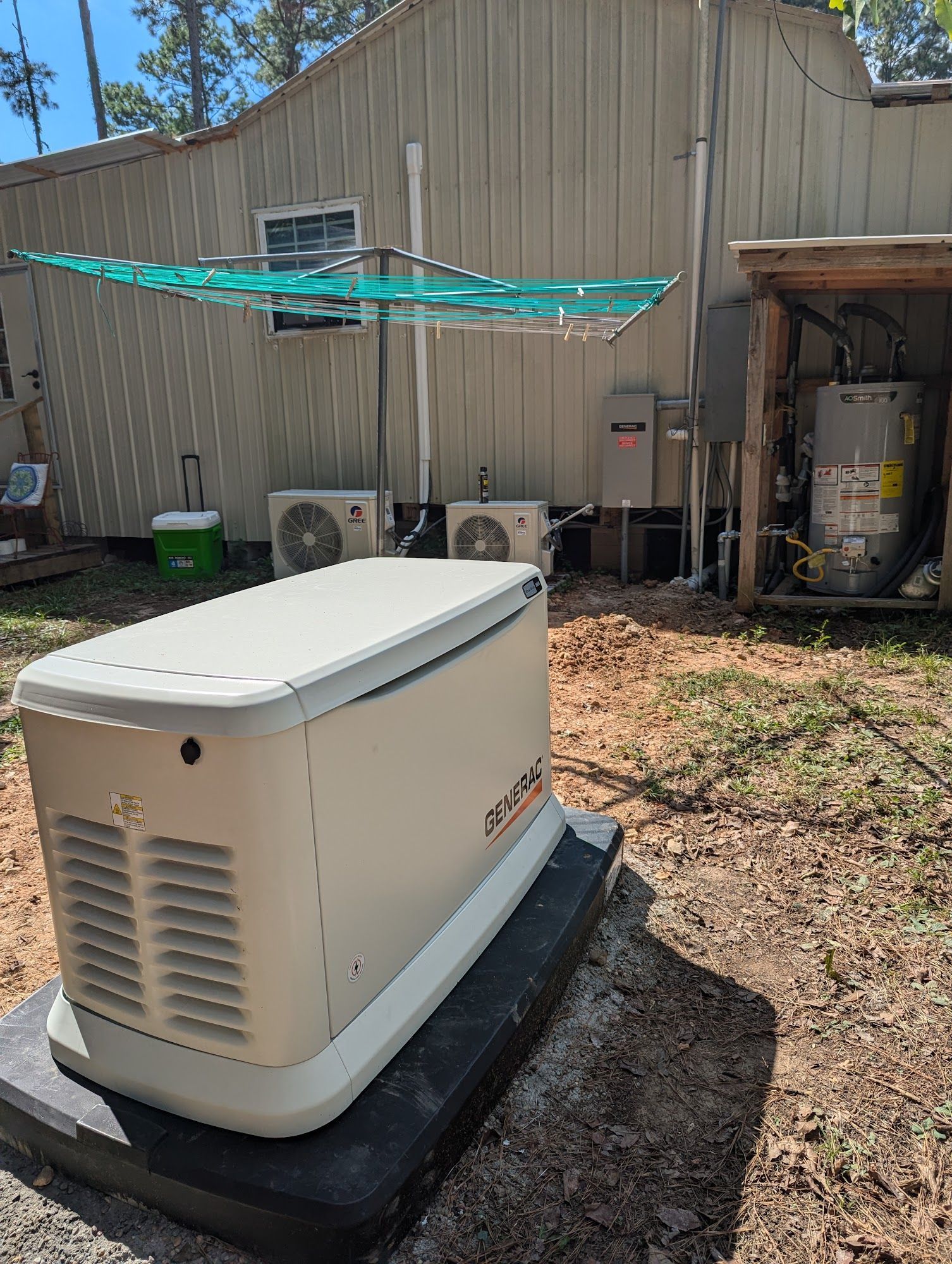 A white generator is sitting on top of a black platform in front of a building.