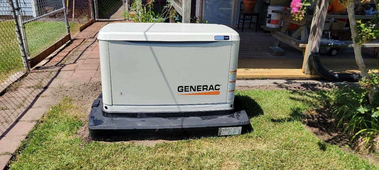 A generator is sitting in the grass in front of a house.