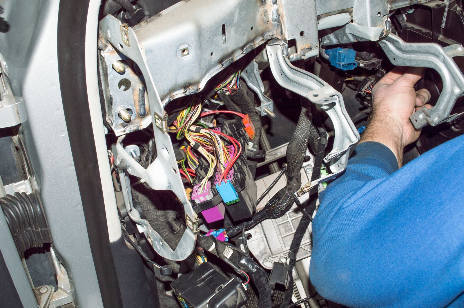 A man in a blue shirt is working on a car