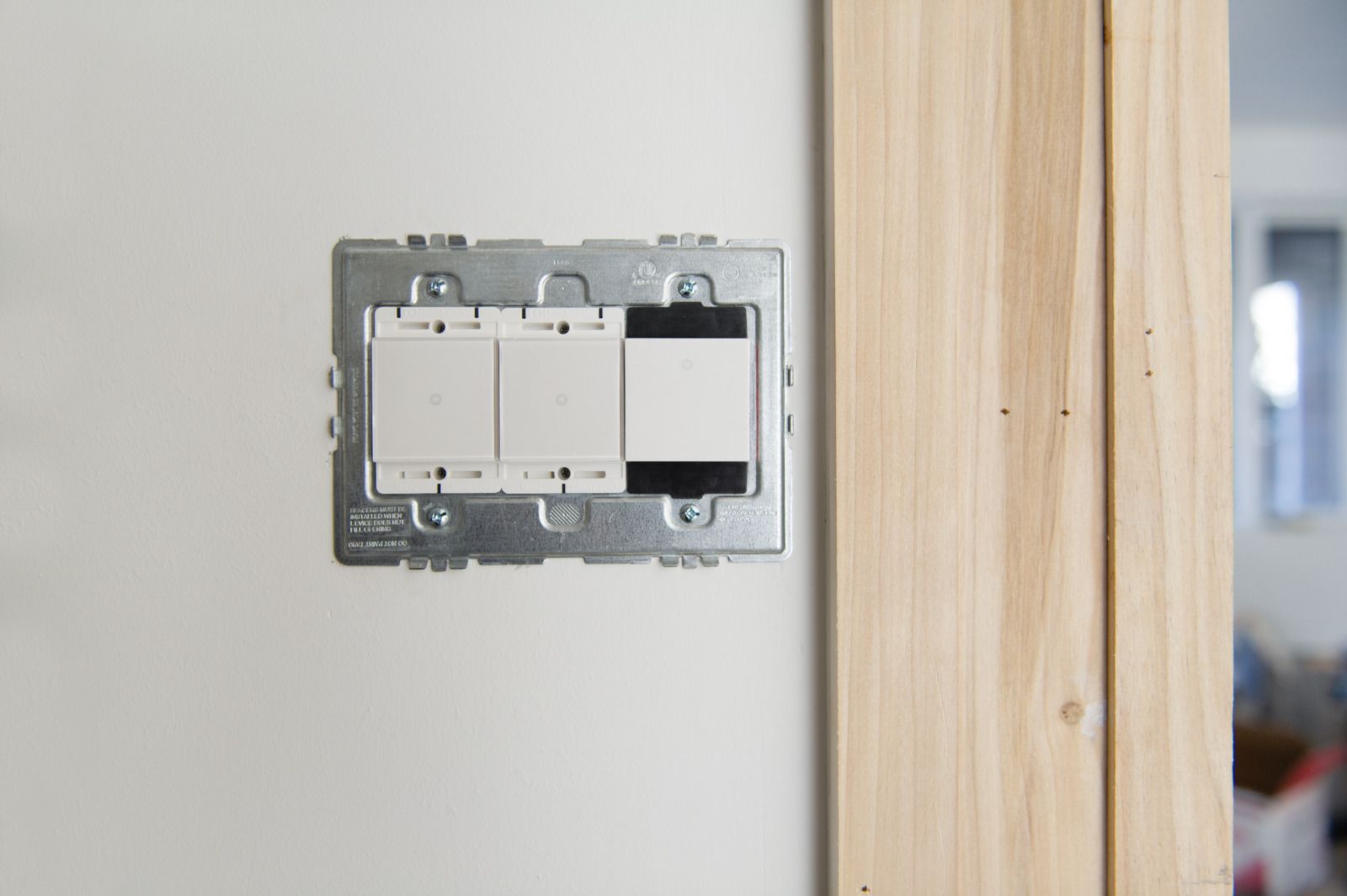 A close up of a light switch on a wall next to a wooden door.