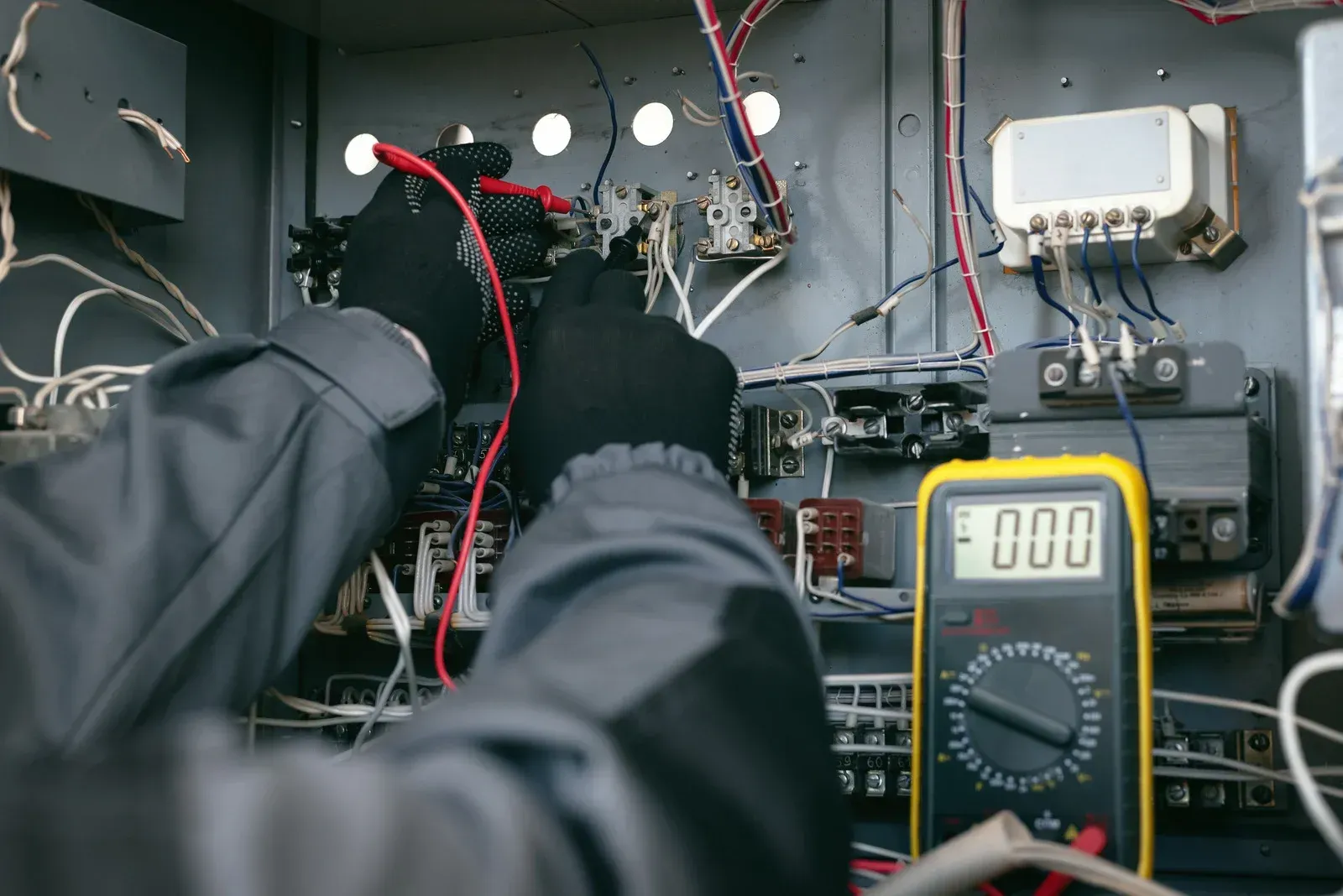 An electrician is using a digital multimeter to test a circuit.
