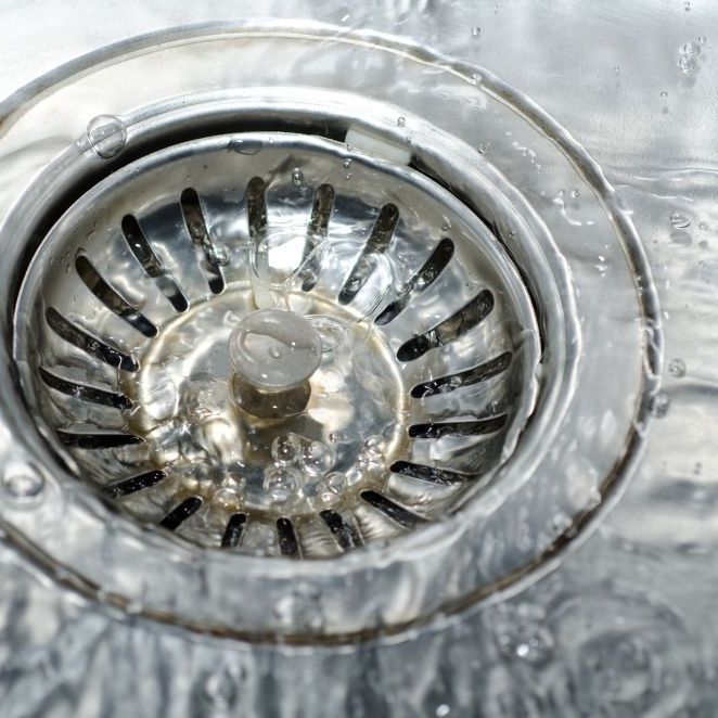 A close up of a sink drain with water coming out of it