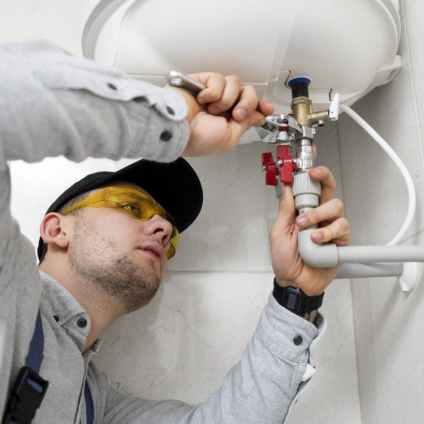 A man wearing safety goggles is fixing a water heater