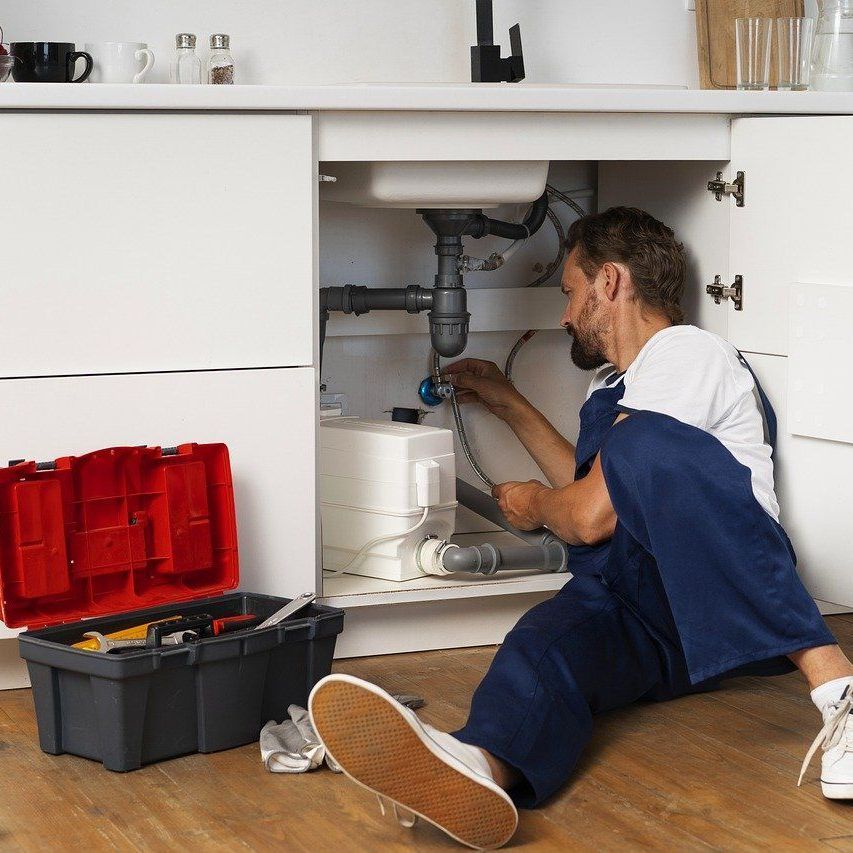 A plumber is fixing a faucet in a kitchen sink in Meriden, CT