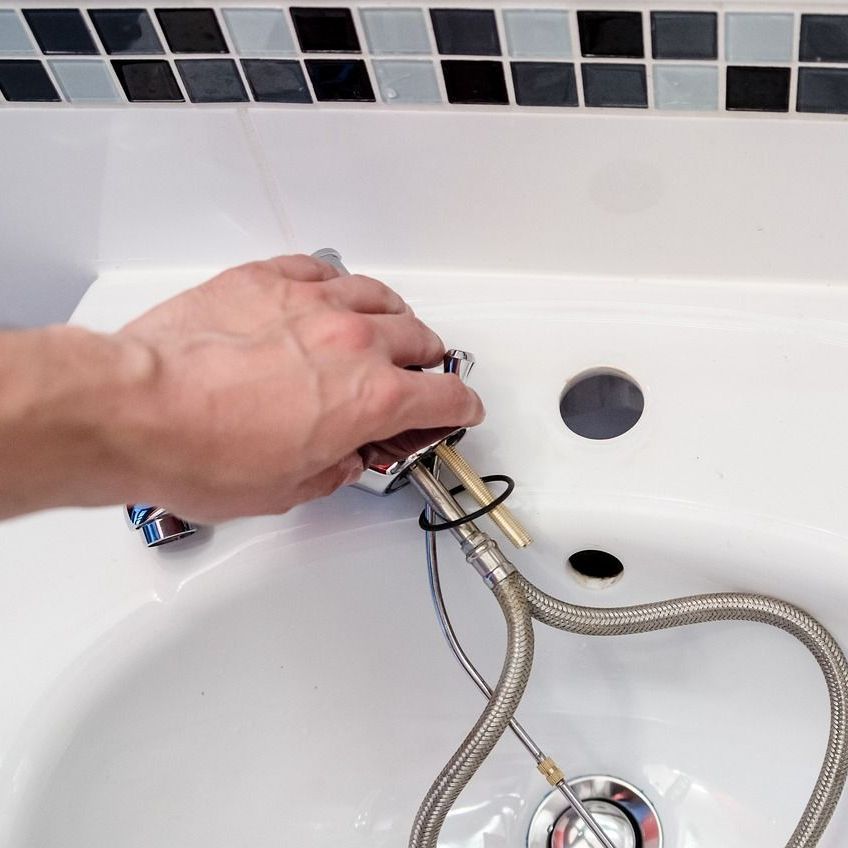 A person is adjusting a knob on a water heater.