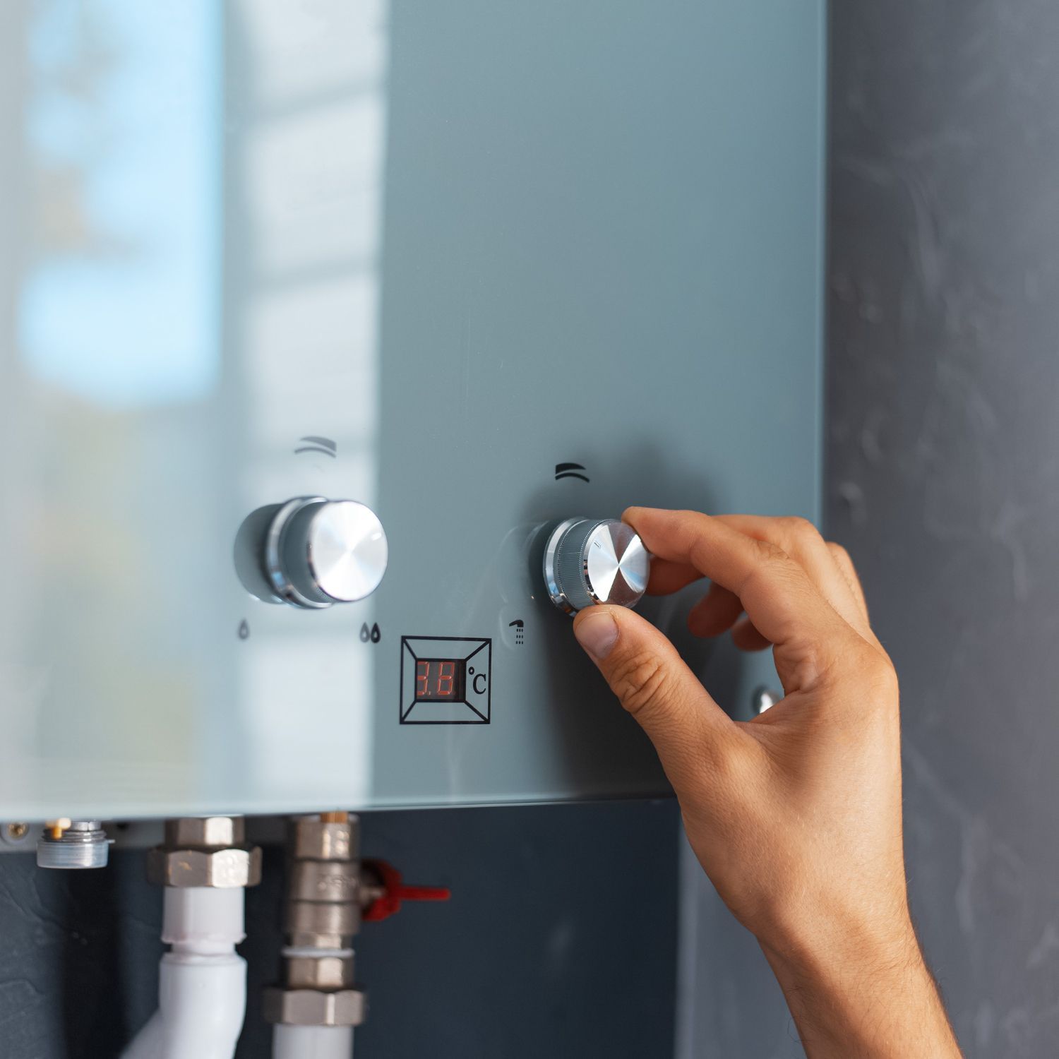 A person is adjusting a knob on a water heater.