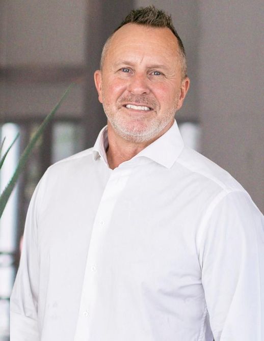 A woman is sitting at a desk with a laptop and a vase of flowers.