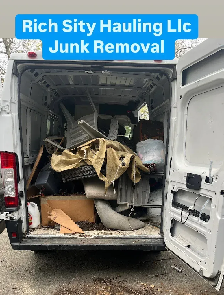 Junk removal truck with open rear loaded with scrap and debris, labeled “Rich City Hauling LLC.”