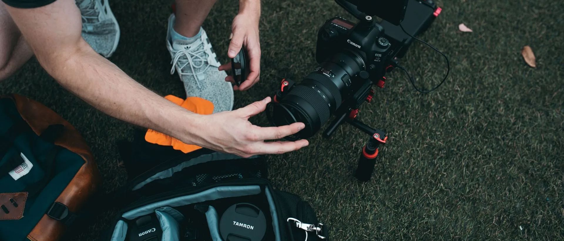 a person is putting a camera lens into a backpack .