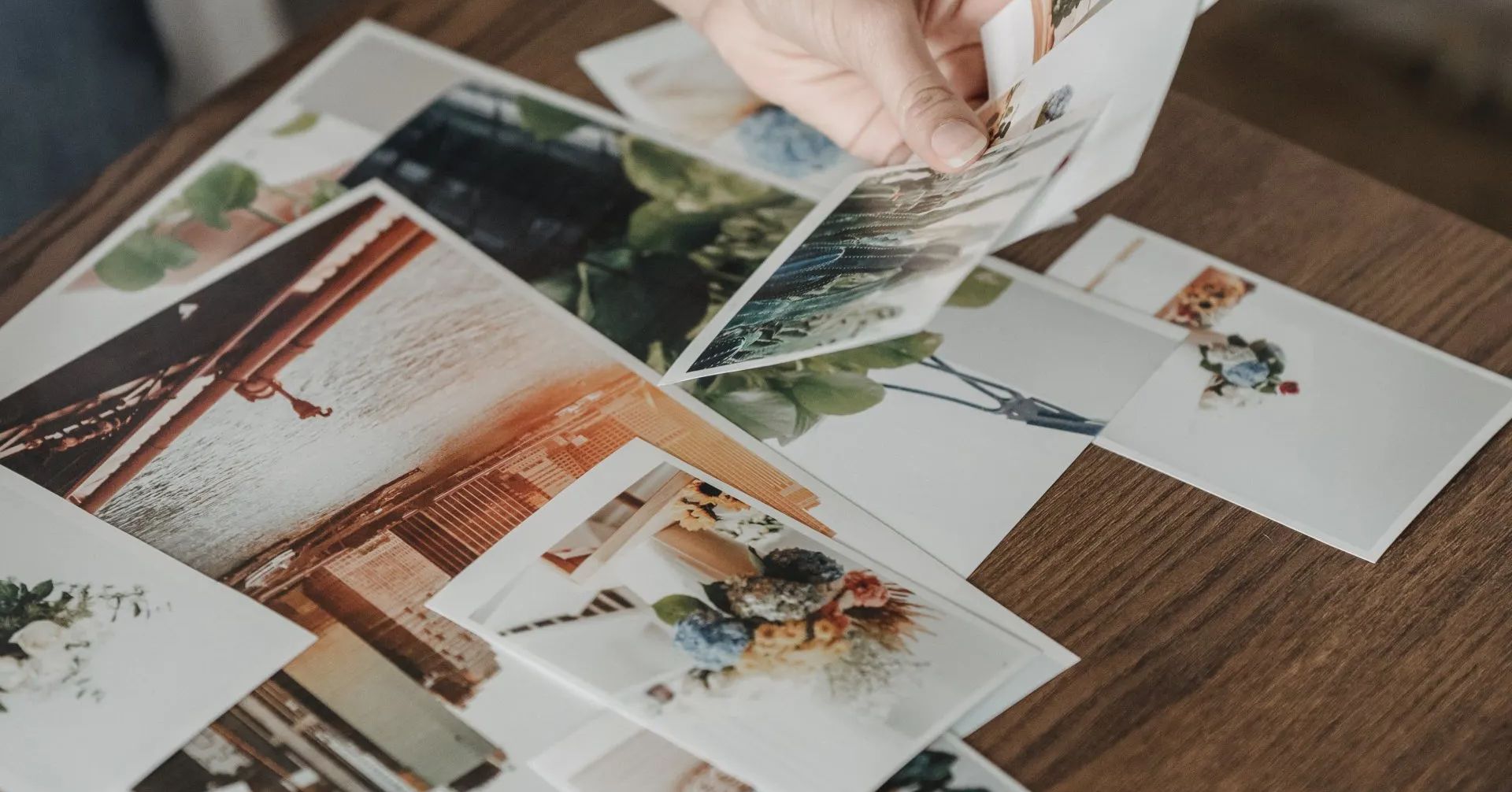 a person is picking up a picture from a pile of pictures on a table .