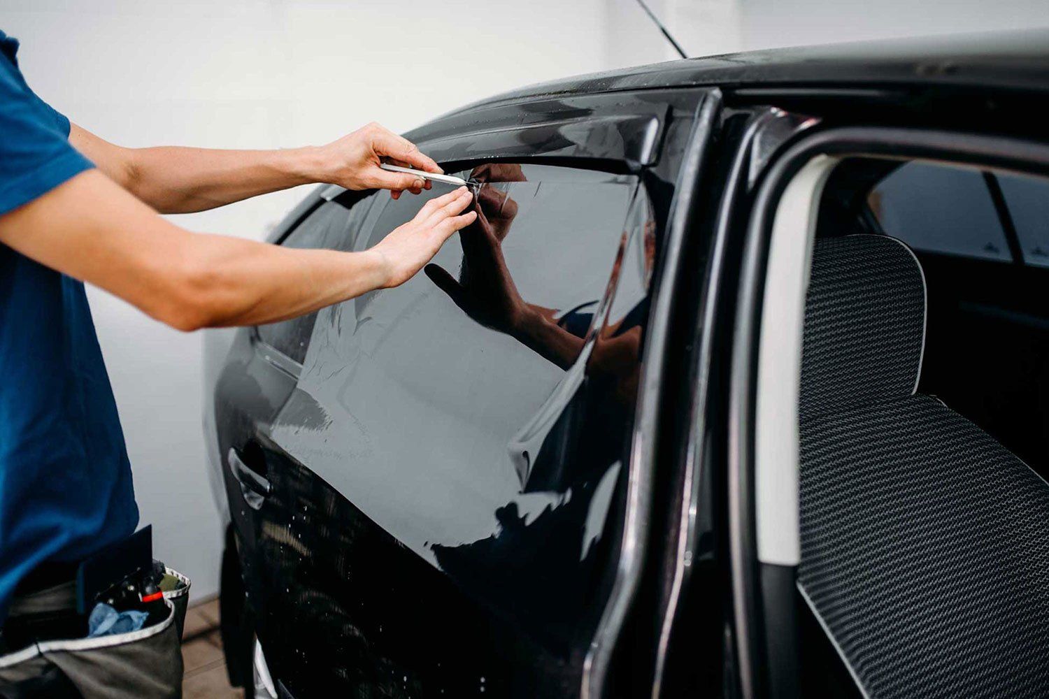 tecnico mentre applica una pellicola ai vetri dell'auto