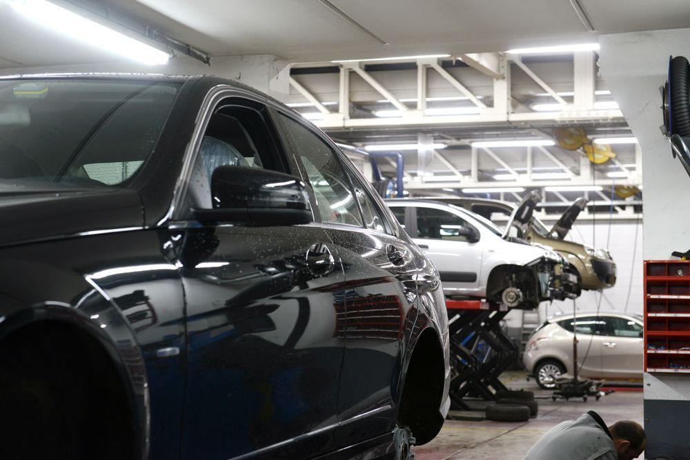 A Black Car is Parked in a Garage With Other Cars — A & J Auto Body Repairs In Port Stephens, NSW