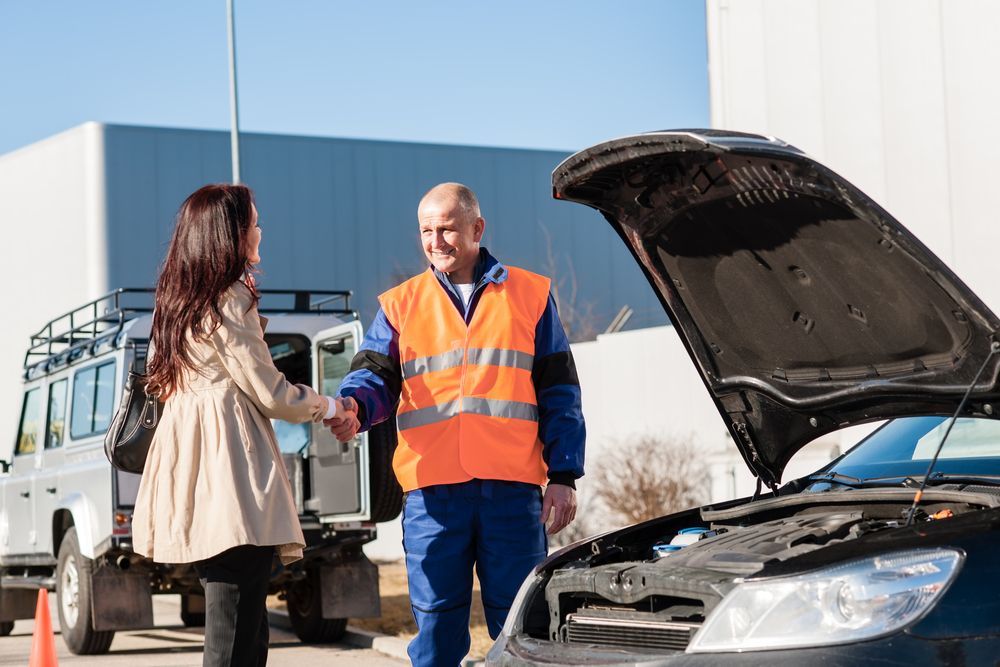A Man is Shaking Hands With a Woman in Front of a Broken Down Car — A & J Auto Body Repairs In Salamander Bay, NSW