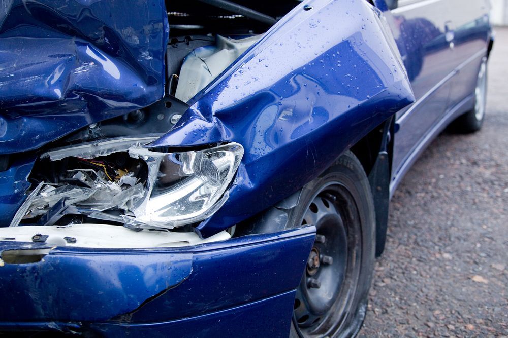 A Blue Car With a Damaged Front End is Parked on the Side of the Road — A & J Auto Body Repairs In Muswellbrook, NSW